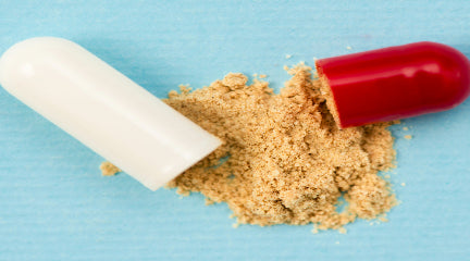 Broken capsule with brown powder on a blue background