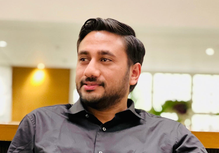 Man wearing a gray shirt with a blurred indoor background